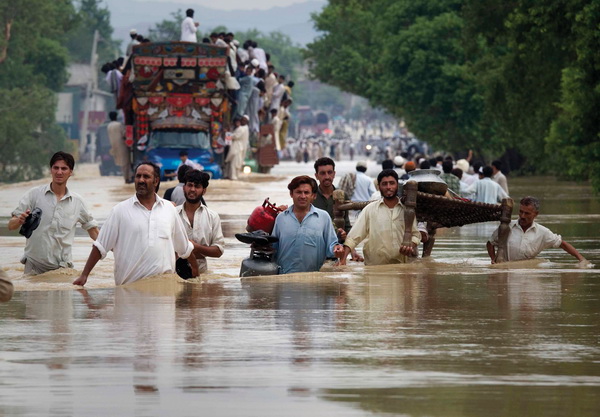 Residents carry their belongings through a flooded road in Risalpur in Pakistan's Northwest Frontier Province